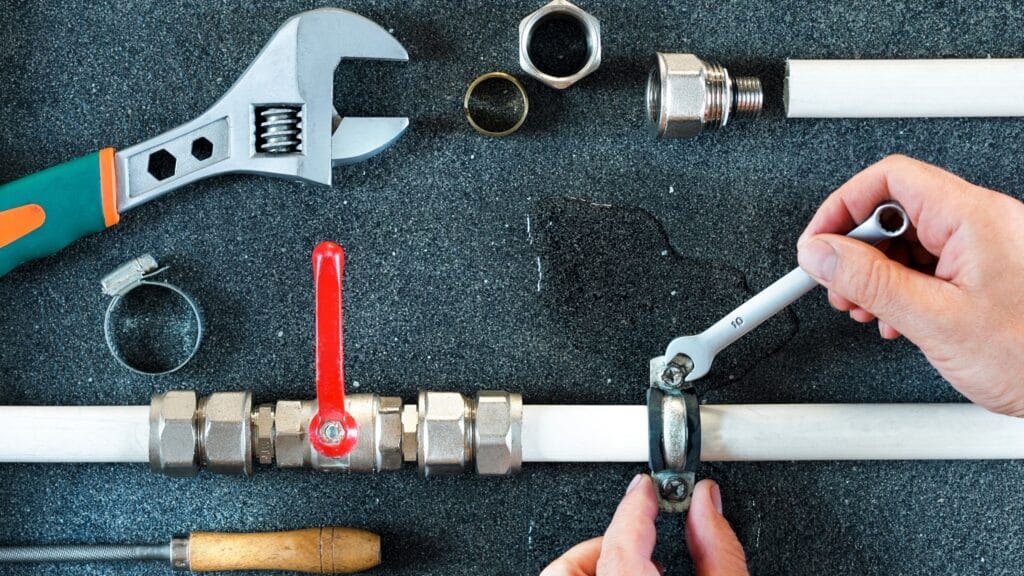 Plumber repairing a pipe valve with an adjustable wrench in Hollywood